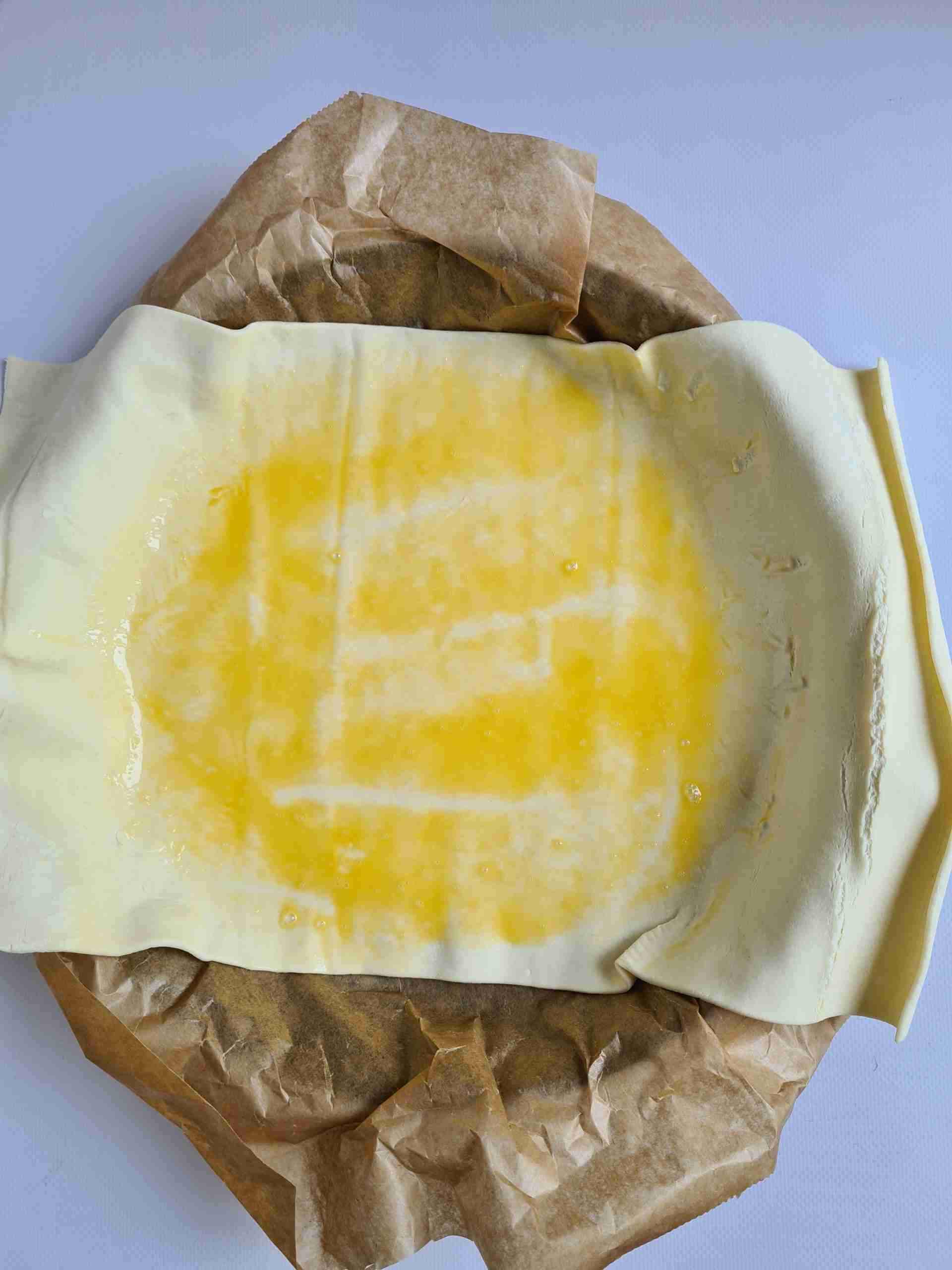 Rol het bladerdeeg op en leg op het bakpapier.